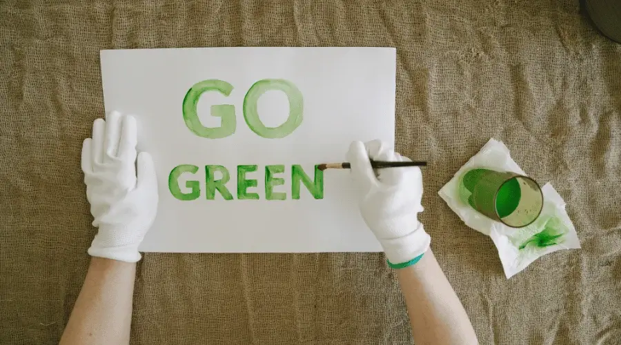 person off camera painting the words 'Go Green' with green paint on paper
